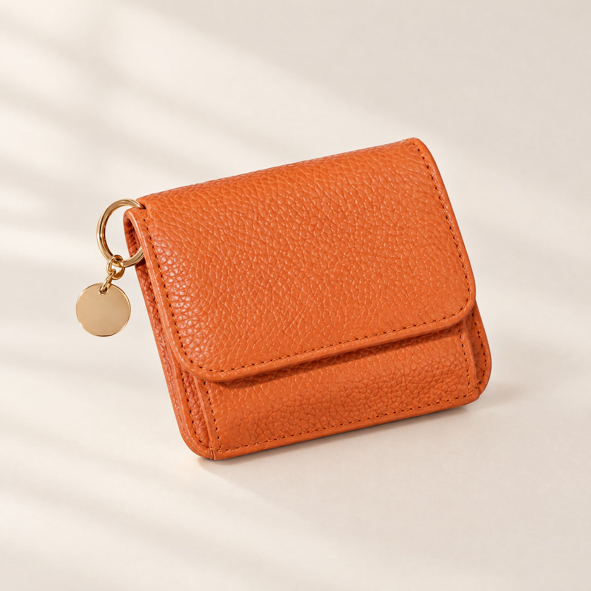 TravelSmart Bella Women's RFID Wallet in orange pebbled leather, closed front view with gold ring and disc charm