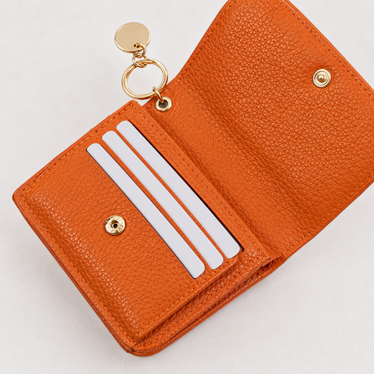 Bella RFID wallet in orange opened to show the snap closure and card slots