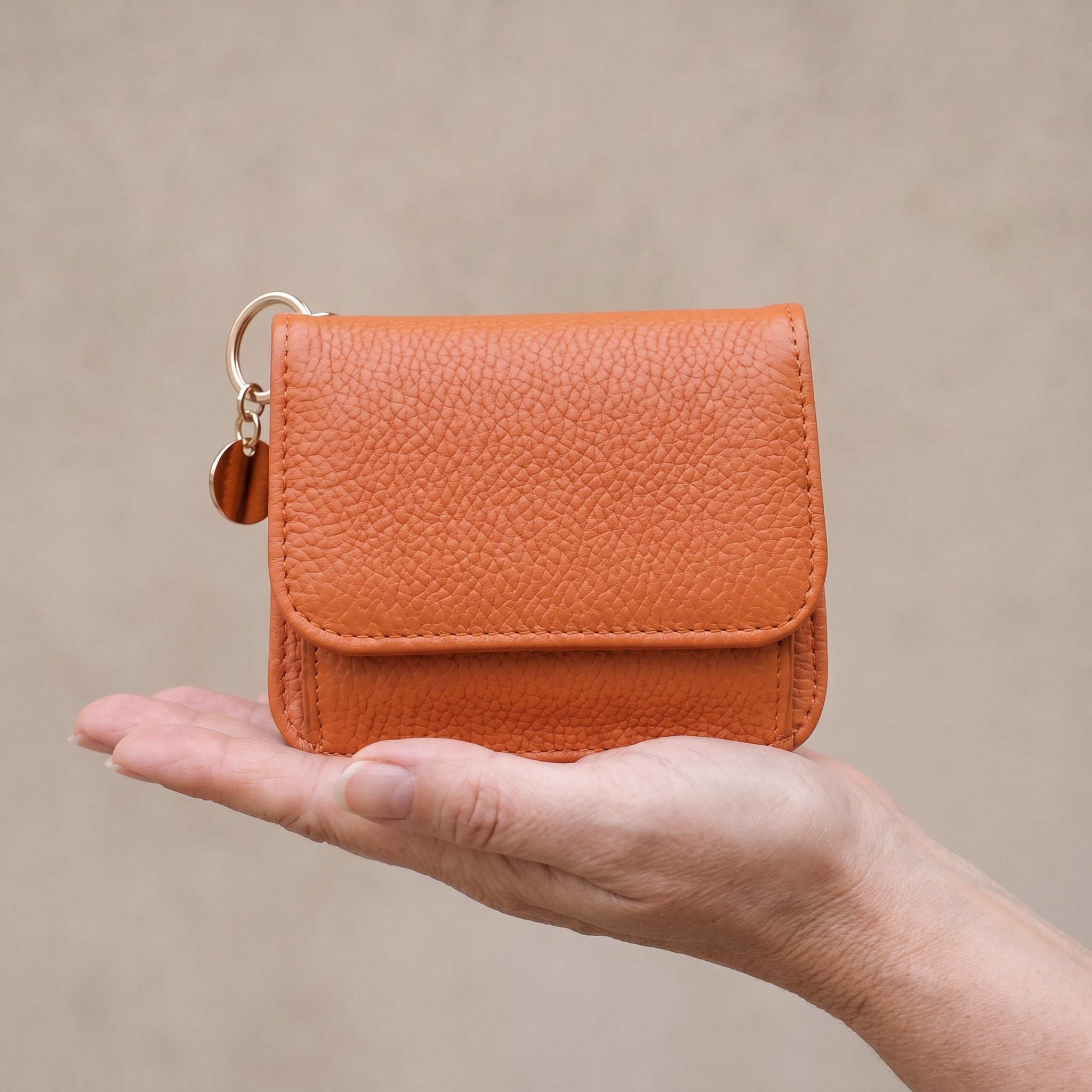 Orange Bella RFID wallet held in an open hand to show its compact size, about 12 x 10 cm